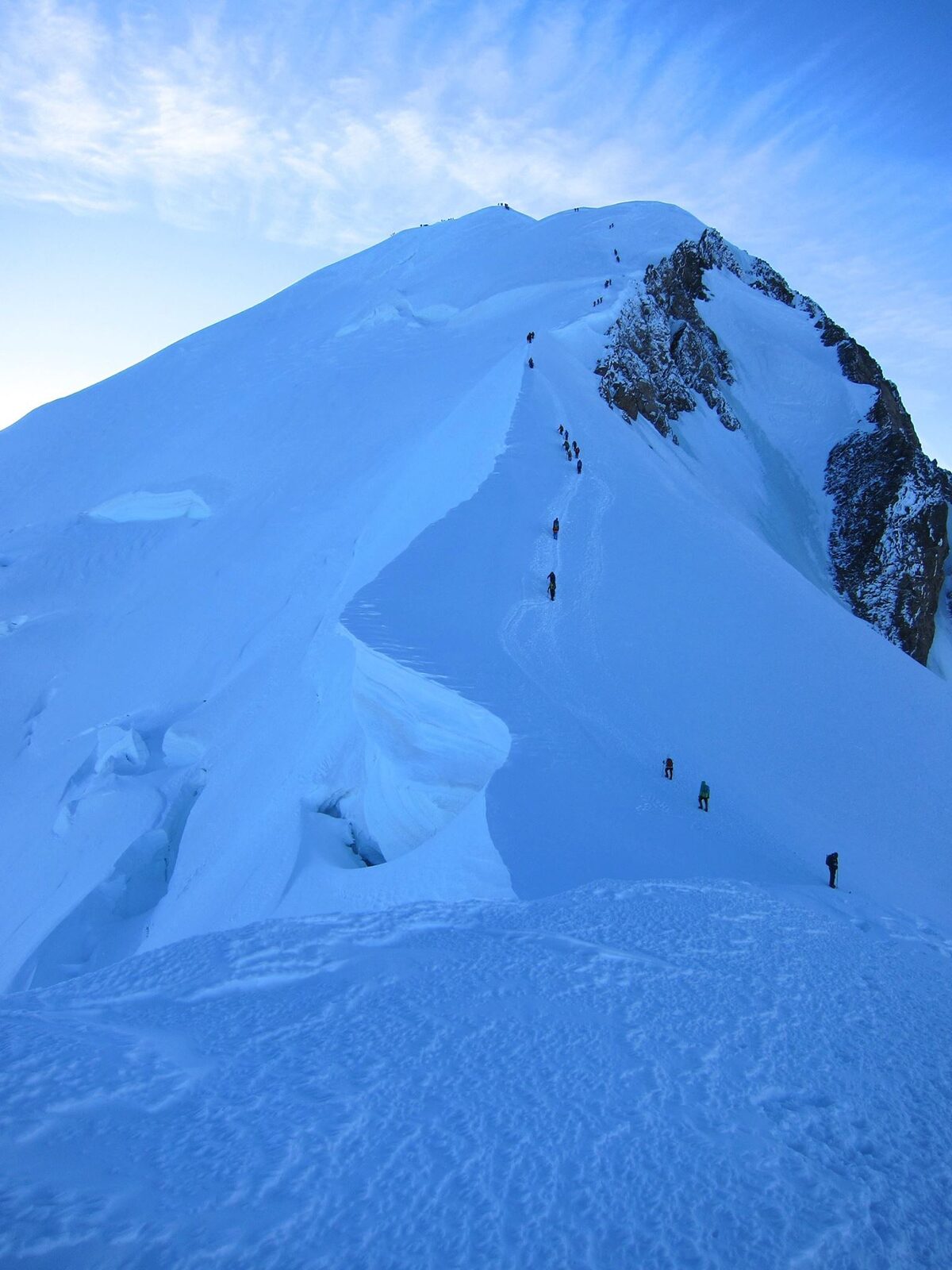 A line of climbers strung out up a broad snow slope on Mont Blanc