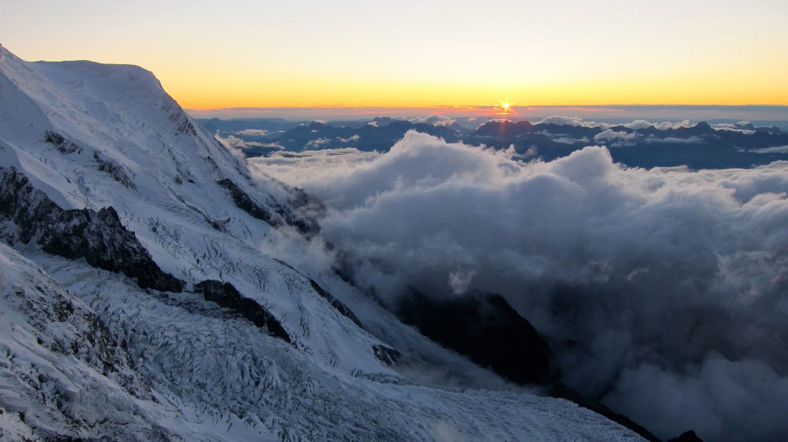 Sunrise breaking over a sea of cloud, seen from high on Mont Blanc