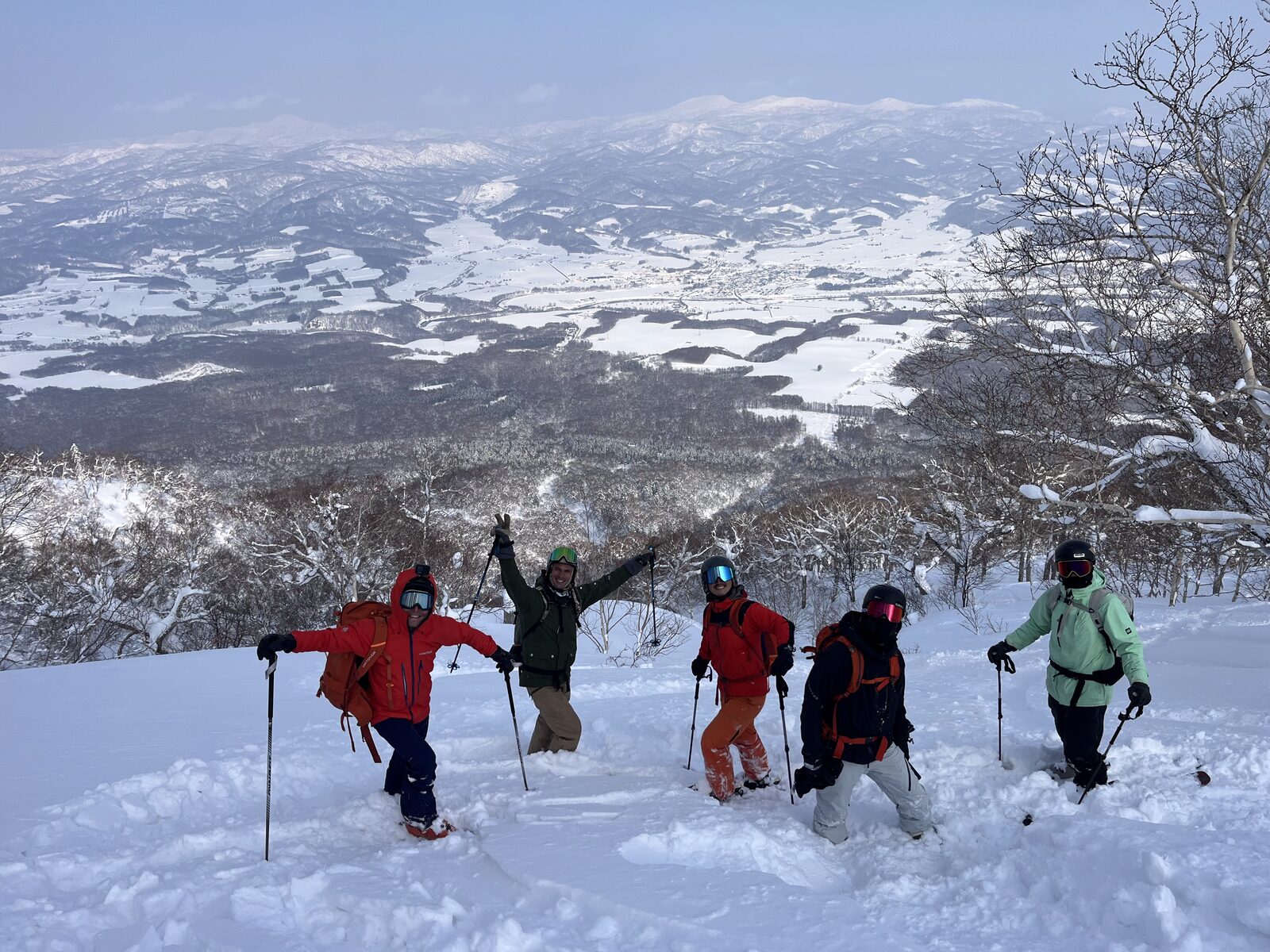 Five skiers above the tree line on Mt. Yotei with the Niseko valley below